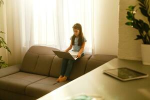 Fernbedienung Unterricht. das Kind lächelt glücklich und bekommt Wissen entfernt. wenig Mädchen Studie online Lernen von Zuhause mit Laptop. online Schule. foto