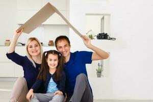 Konzept Gehäuse ein jung Familie. Mutter Vater und Kind im Neu Haus mit ein Dach foto