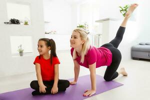 Mutter und Tochter üben online Yoga Lektion beim Zuhause beim Quarantäne Isolierung Zeitraum während Coronavirus Pandemie. Familie tun Sport zusammen online von heim. gesund Lebensstil foto