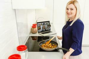 ein Frau Kochen und mit das Laptop im das Küche foto