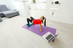 Quarantäne beim heim. wenig Mädchen tun Yoga online auf ein Laptop während selbst Isolierung Quarantäne foto