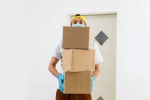 ein Mann ein medizinisch Maske und Blau Gummi Handschuhe mit ein Kasten, ein Paket im seine Hände. Essen Lieferung während das Quarantäne von das Coronavirus Pandemie. Zuhause Lieferung, online Befehl. online Einkaufen . foto