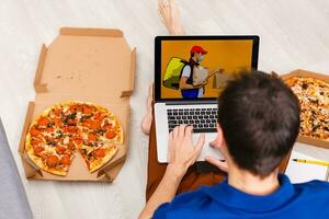 Mann mit Laptop zum online Essen bestellen während Quarantäne, Nahaufnahme. Lieferung Bedienung foto