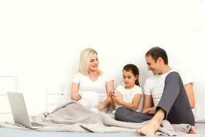 Familie Lügen im Bett zusammen mit Digital Geräte foto