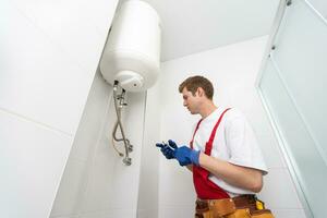 Nahansicht von Klempner mit Schraubendreher während Festsetzung Kessel oder Wasser Heizung, Arbeiten auf Heizung System im Wohnung foto