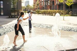 auf ein heiß Tag, Kinder Lauf und haben Spaß beim das Stadt Brunnen. Freizeit Zeit Konzept. Sommer- Feiertage. glücklich Kindheit. foto