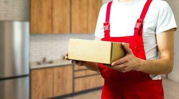 jung lächelnd logistisch Lieferung Mann im rot Uniform halten das Box foto