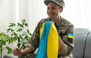 ein ukrainisch Militär- Mann hält das National Flagge im seine Hände wie ein Symbol von stark. Krieg im Ukraine. foto