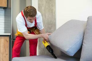 Mann trocken Reiniger Mitarbeiter Hand im schützend Gummi Handschuh Reinigung Sofa mit beruflich Extraktion Methode. früh Frühling regulär Aufräumen. kommerziell Reinigung Unternehmen Konzept. foto