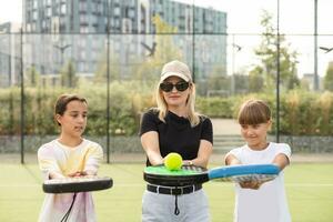 aktiv jung Frau üben Padel Tennis mit Gruppe von Spieler im das Tennis Gericht draußen foto