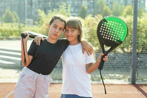 Teenager Mädchen mit Schläger und Bälle Stehen im Padel Gericht, suchen beim Kamera und lächelnd. foto