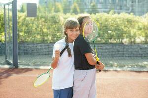 glücklich sportlich elementar Schule Alter Mädchen, Kind spielen Badminton, halten ein Schläger Herstellung komisch Gesichter, Porträt, Lebensstil. Sport, Übung und gesund draussen Aktivitäten Freizeit Konzept, einer Person foto