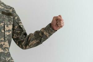 Hand im tarnen zeigt an Geste auf grau Hintergrund. Finger geballt in ein Faust. einfrieren Geste im das Militär. Heer Geste Sprache. foto