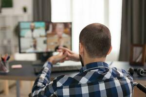 Unternehmer im Rollstuhl chatten mit Mitarbeiter auf Video Konferenz. jung ungültig Freiberufler tun seine Geschäft online, mit hoch Technologie, Sitzung im seine Wohnung, Arbeiten entfernt im Besondere Bedingungen. foto