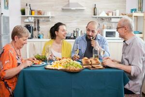 Tochter lächelnd beim Vater im Küche während Familie Mittagessen. Mann Essen köstlich Lebensmittel. glücklich Senior Mann beim Essen Tisch. lecker geröstet Kartoffeln. foto