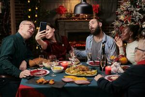 Menschen nehmen Bilder beim festlich Abendessen mit hausgemacht Essen und Brille von Wein, Herstellung Erinnerungen während Weihnachten Vorabend Winter Urlaub. vielfältig Personen haben Spaß mit Fotos auf Telefon beim heim.
