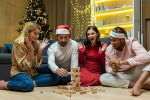 Neu Jahr Party, verschiedene freunde beim Zuhause auf Fußboden spielen Spiel, Männer und Frauen lächelnd und glücklich zusammen zum Weihnachten verbringen Zeit. foto