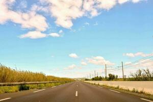 ein lange leeren Straße mit ein Blau Himmel und Wolken foto