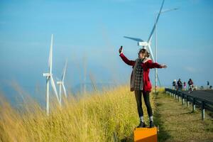 auf das Hintergrund von Windmühlen, ein jung Frau im ein rot Jacke ist genießen ihr Winter Urlaub. foto