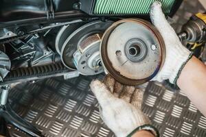 Mechaniker überprüfen das automatische Getriebesystem oder die hintere Kupplungsscheibe von Rollermotorrädern in der Garage. wartung, reparaturmotorradkonzept in der garage. selektiver fokus foto