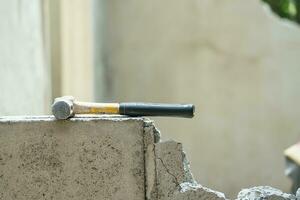 Hammer stellen es auf Absturz Backstein Mauer im Konstruktion Seite? ˅ foto