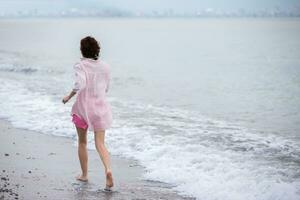 ein mittleren Alters Frau läuft entlang das Strand. foto