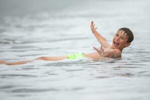 glücklich Junge schwimmt im das Meer. Theaterstücke mit Wellen und Spritzer. foto