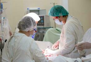 chirurgisch Abteilung von das Krankenhaus. Ärzte ausführen ein Betrieb auf ein chirurgisch Tabelle zum ein geduldig. foto