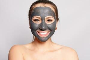 Porträt von schön Mädchen entfernen kosmetisch schwarz Peeling Maske foto