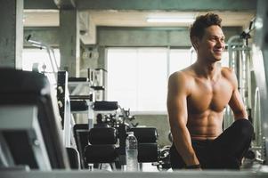 Ein gutaussehender junger Mann, der in einem Fitnessstudio posiert