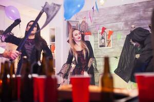 heiter Vampir Frau beim ein Halloween Party. Bier Kappen foto