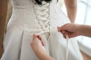 schließen oben von binden Bogen auf elegant Weiß Braut- Hochzeit Kleid foto