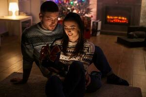 heiter Paar im ein dunkel Zimmer aufgeregt Über Über Magie Weihnachten Geschenk. foto