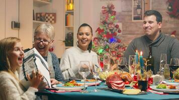 Oma geben ihr wenig großartig Tochter ein Geschenk beim Weihnachten Wiedervereinigung. traditionell festlich Weihnachten Abendessen im Mehrgenerationenhaus Familie. genießen Weihnachten Mahlzeit Fest im dekoriert Zimmer. groß Familie Wiedervereinigung foto