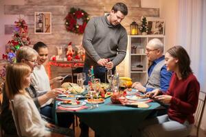 Vater Öffnung ein Flasche von Wein beim Weihnachten Familie Abendessen. köstlich Lebensmittel. foto