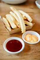 Französisch Fritten oder Kartoffel Chips mit Tomate Soße und Käse Soße auf hölzern Schreibtisch. foto
