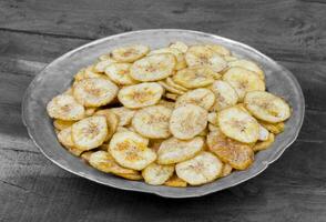 Banane Chips Beliebt tief gebraten Tee Zeit Snack auf dunkel hölzern Hintergrund foto