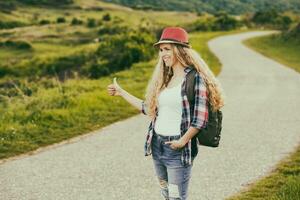 schön jung Frau Trampen beim das Land Straße. foto