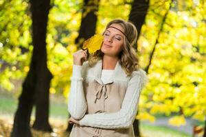 schön Boho Mädchen halten Herbst Blatt und genießt im das Park. foto