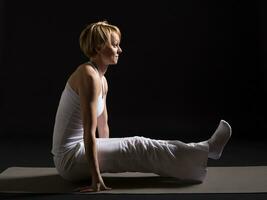 Frau ausüben Yoga Innen- auf schwarz Hintergrund, foto