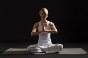 Frau ausüben Yoga Innen- auf schwarz Hintergrund, foto