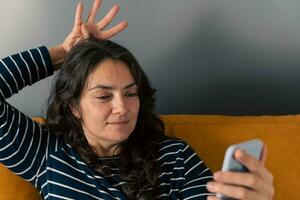 ein lächelnd Frau genießen ein Video Anruf auf ihr Smartphone und zeigen ein Krone auf ihr Kopf foto