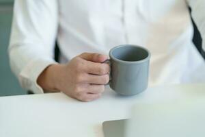 glücklich jung Geschäft Mann. Trinken Kaffee und Arbeiten auf Laptop Computer während Sitzung beim Büro foto