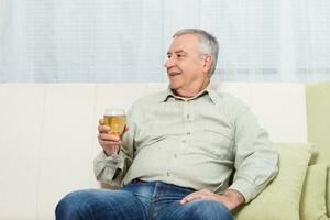 Senior Mann genießt Trinken Wein beim heim. foto