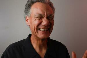 älter reifen Mann gegen ein grau Hintergrund brechen aus im Lachen foto