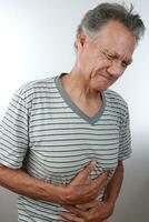 älter reifen Mann halten seine Magenschmerzen weil von Schmerzen foto