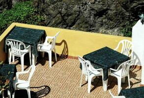 ein Terrasse mit Tabellen und Stühle auf das Seite von ein Cliff foto