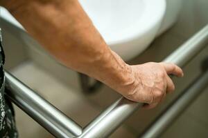 asiatisch Alten Frau geduldig verwenden Toilette Badezimmer Griff Sicherheit im Pflege- Krankenhaus, gesund stark medizinisch Konzept. foto