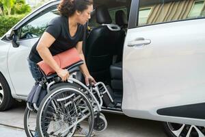 asiatisch Behinderung Frau auf Rollstuhl bekommen im ihr Auto, Barrierefreiheit Konzept. foto