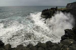 Wellen abstürzen gegen das Felsen beim das Kante von das Ozean foto